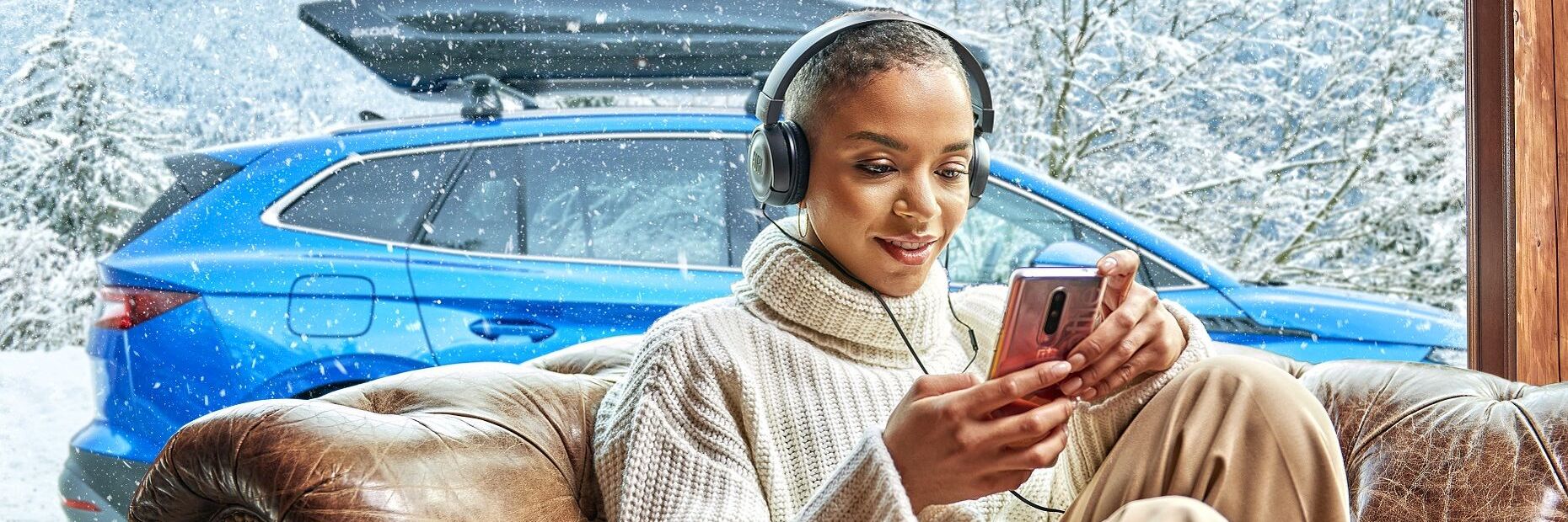 Senhora de fones dentro de casa com Škoda estacionado atrás