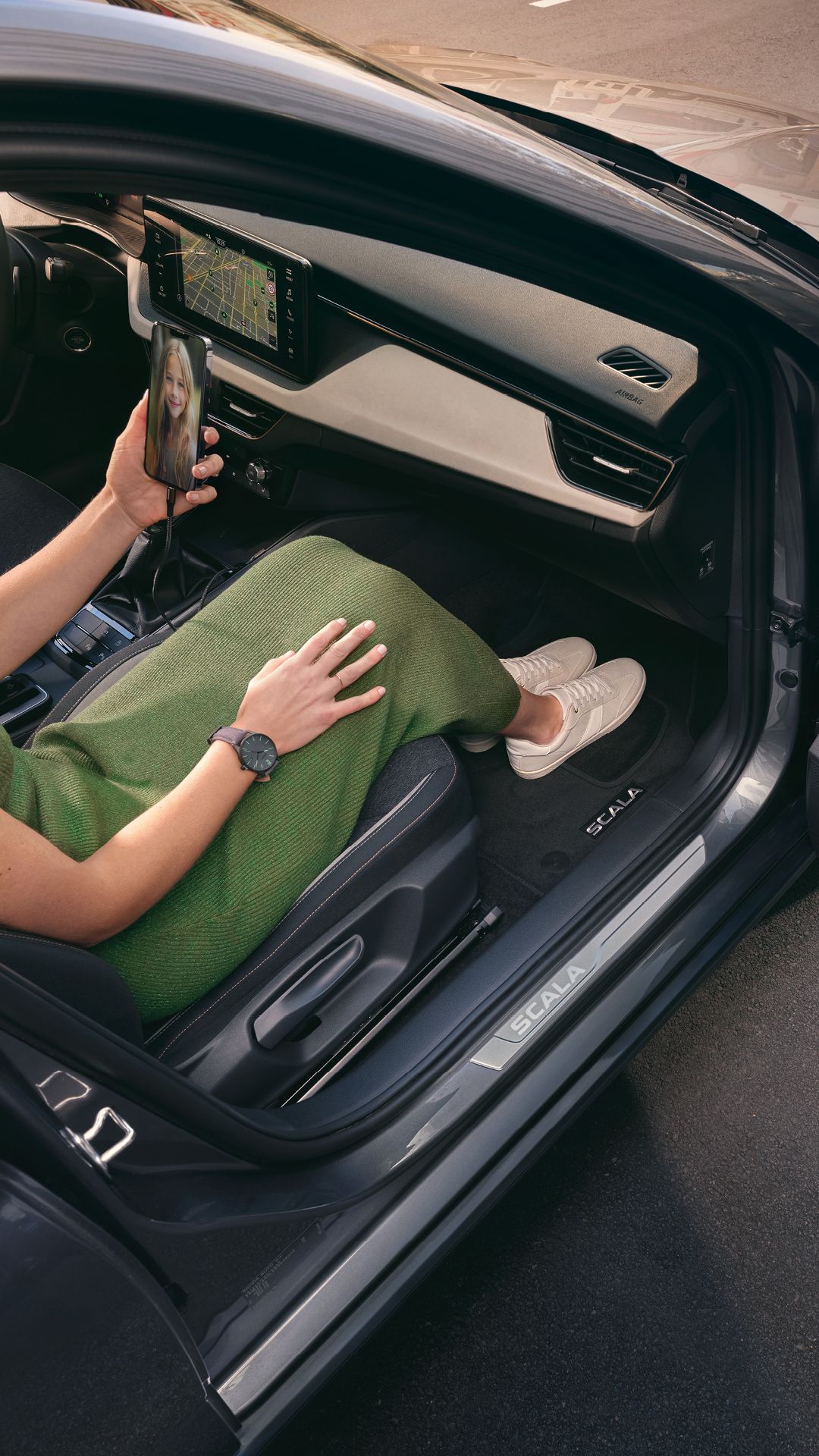 Eine Frau in einem Škoda Scala blickt auf ihr Smartphone