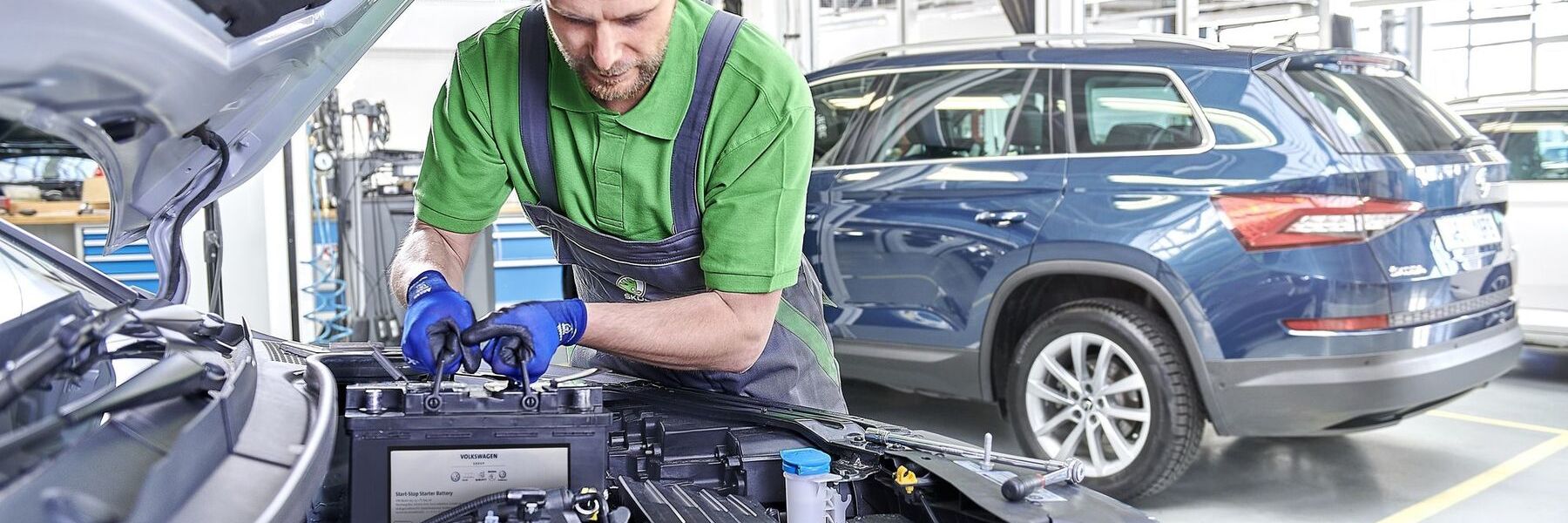 Ein Škoda Mechaniker beim Tausch der Starterbatterie.
