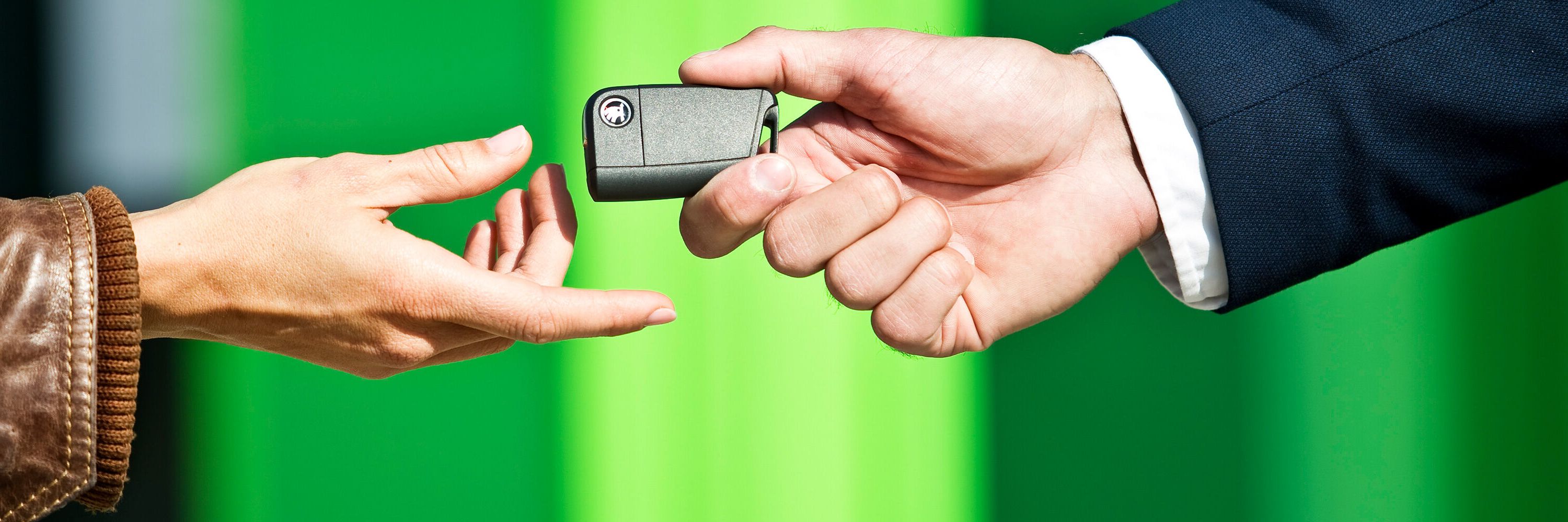Grande plano de duas mãos onde é entregue uma chave de um Škoda 