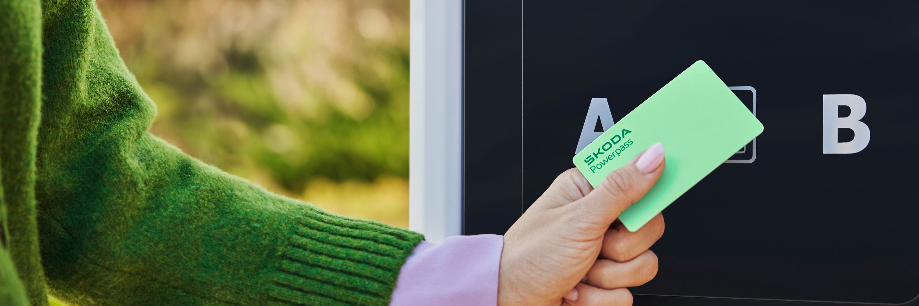 Eine Person hält die Škoda Powerpass-Karte an eine Ladesäule