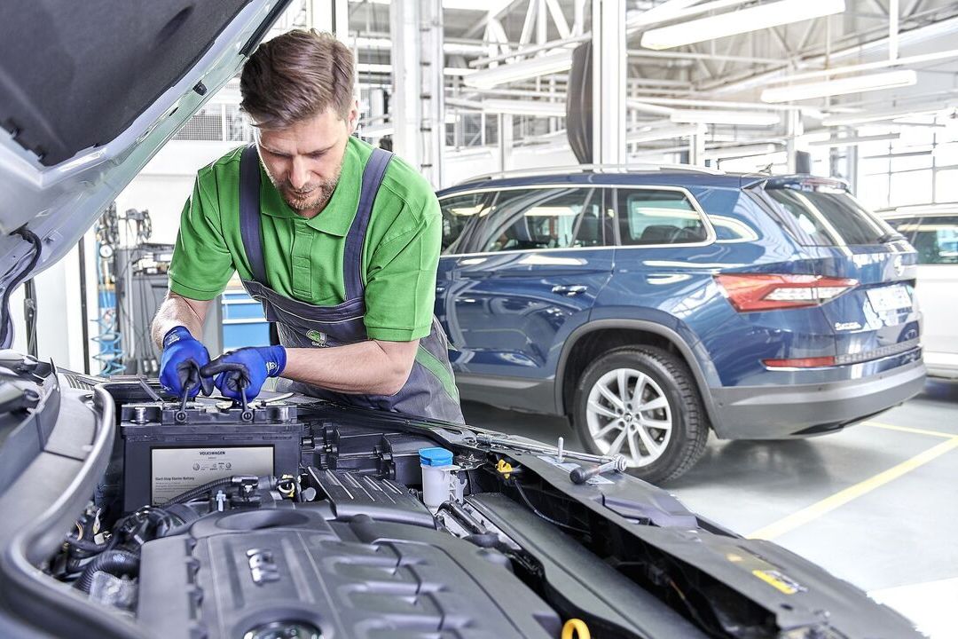 Ein Škoda Mechaniker beim Tausch der Starterbatterie.