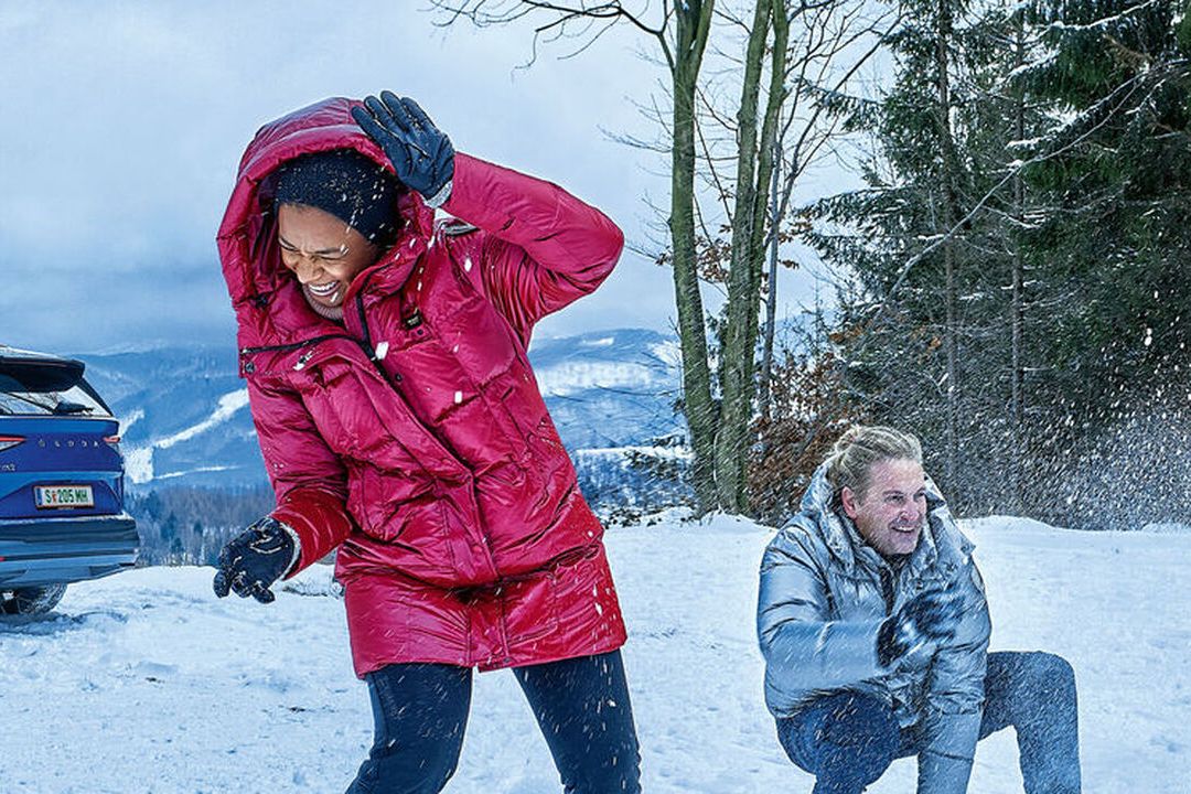 Familie spielt vor einem Škoda im Schnee