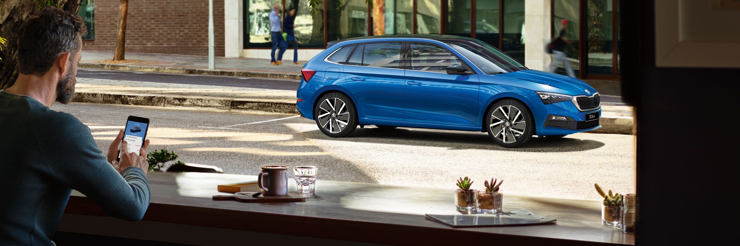 Škoda azul visto por um homem a partir de um café 